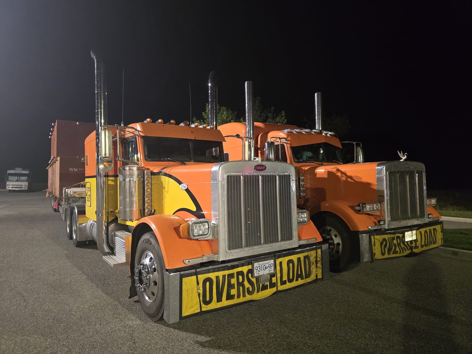 Two Oracle Carriers trucks staged with oversize load banners